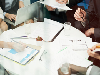 Businessman analyzing a wall with many financial charts and reports, he is underlining text with a marker